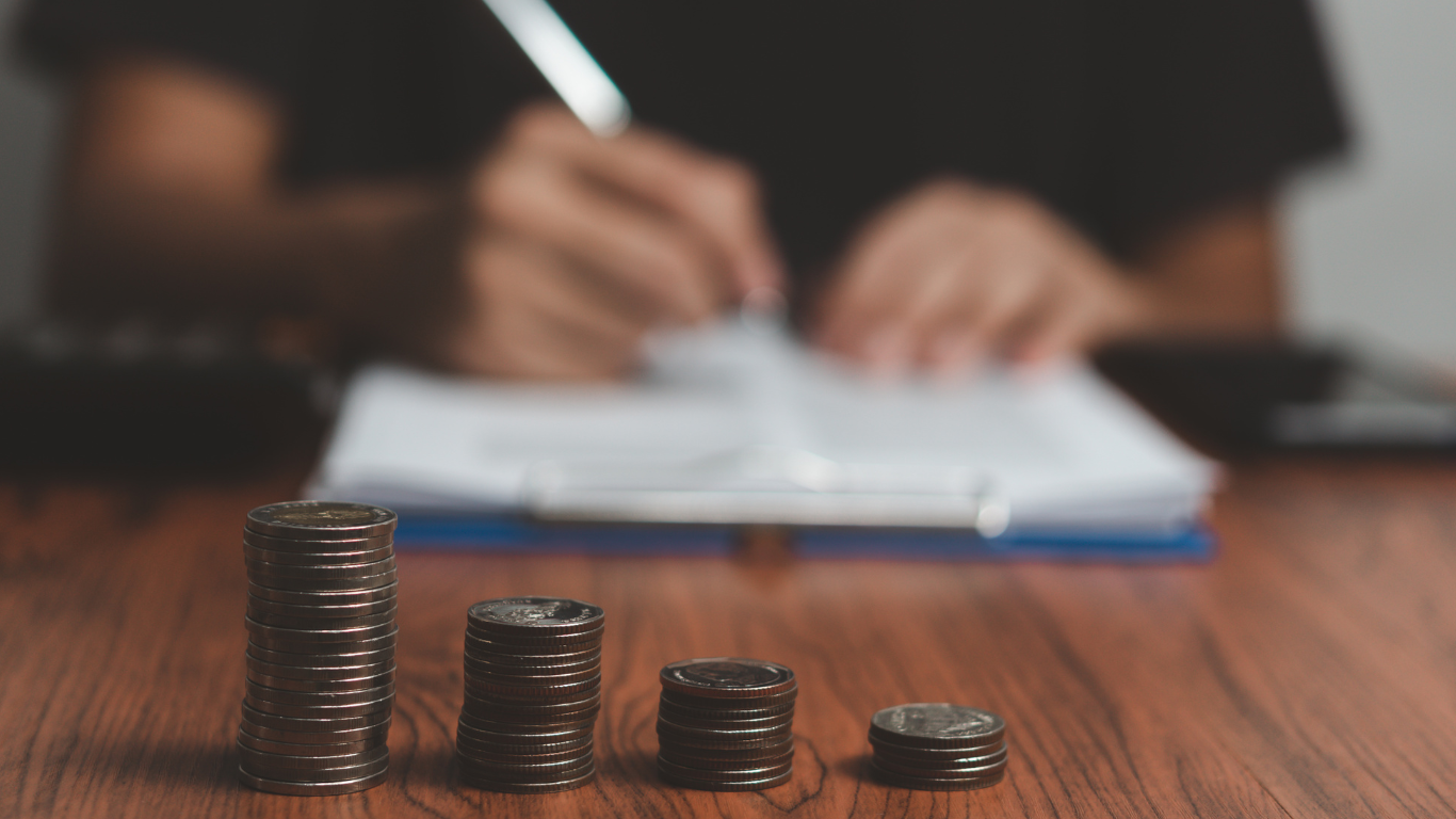 coin stacks in front of someone writing in a notebook